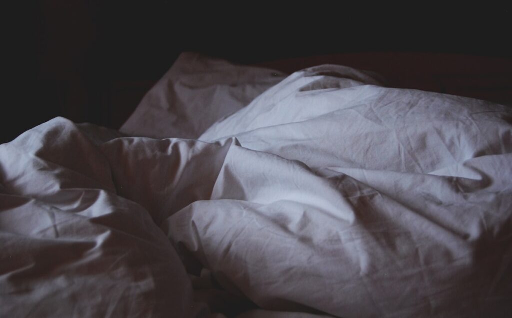 Bed with white blanket representing sleepless nights and insomnia
